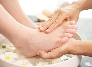 foot washing in spa before treatment. spa treatment and product for female feet and hand spa. white flowers in ceramic bowl with water for aromatherapy at spa.